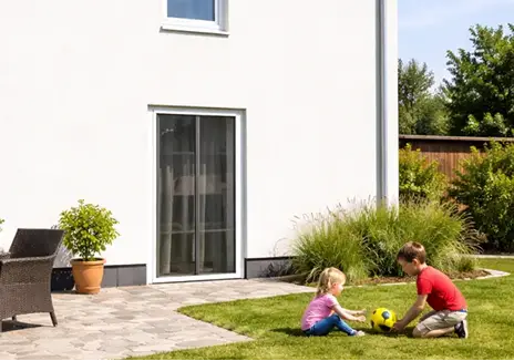 Kinder spielen im Garten vor einer Terrassentür mit Insektenschutzgitter